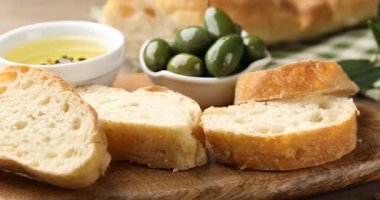 Ciabatta dilimleri, yağ ve zeytinler ahşap masada. Kamera sola hareket ediyor