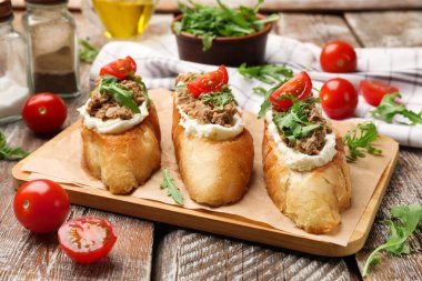 Lezzetli bruschettalar, ton balığı, krem peynir ve domatesler ahşap masada, yakın plan.