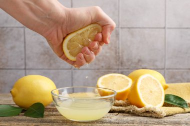 Bir kadın ahşap masada limondan klozete meyve suyu sıkıyor.