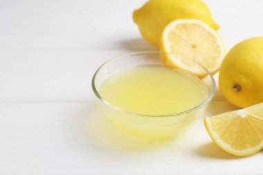 Bardakta limon suyu ve beyaz ahşap masada taze limon, yakın plan. Metin için boşluk
