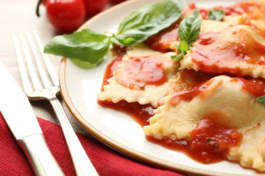 Hafif ahşap masada servis edilen domates soslu ve fesleğenli lezzetli ravioli.