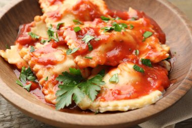 Domates soslu lezzetli ravioli ve ahşap masada maydanoz, yakın plan.