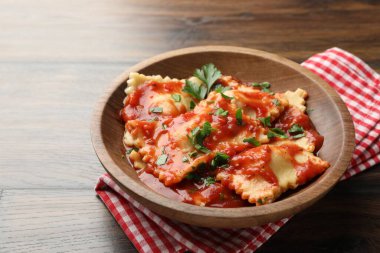 Domates soslu lezzetli ravioli ve ahşap masada maydanoz, yakın plan.