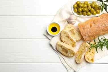 Taze kesilmiş ciabatta, yağ, zeytin, sarımsak ve biberiye beyaz ahşap masa, üst manzara. Metin için boşluk