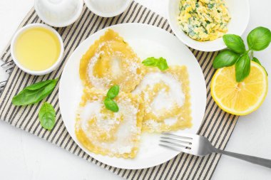 Beyaz masada servis edilen krema soslu ve fesleğenli lezzetli ravioli.