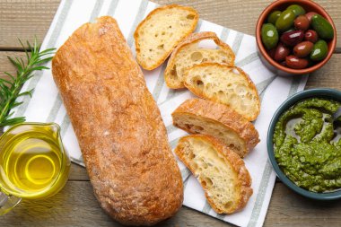 Kesme ciabatta, baharatlar ve zeytinler ahşap masa, düz uzanma