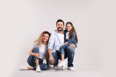 Mutlu ebeveynler ve kızları gri arka planda sarılıyorlar. Aile bağı