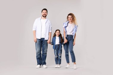 Mutlu aile gri arka planda el ele tutuşuyor.