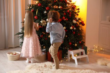 Evde Noel ağacı süsleyen sevimli çocuklar, arka manzara.