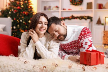 Hediye kutusu olan mutlu çift Noel için dekore edilmiş odada birlikte vakit geçiriyor.