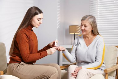 Diyabet. Evdeki koltukta annesinin kan şekerini tükenmez kalemle kontrol eden bir kız.