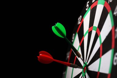 Siyah arka planda dartları olan dart tahtası, yakın plan. Metin için boşluk