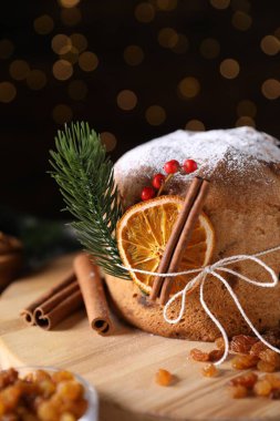 Noel yemeği. Lezzetli Panettone pastası, malzemeler ve arka planda arka planda bulanık ışıklı şenlikli dekor, yakın plan. Bokeh etkisi