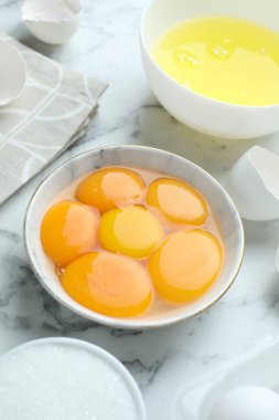 Kırık yumurtalar, sarılar, beyazlar ve şeker beyaz mermer masada, yakın plan.