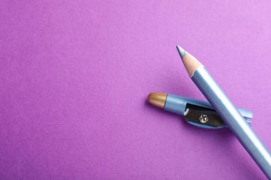 Açık mavi göz kalemi ve mor arka planda keskinleştirici, üst manzara. Metin için boşluk