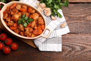 Pişirme kabında nefis pişirilmiş güveç ve ahşap masada taze malzemeler, düz yatak. Metin için boşluk