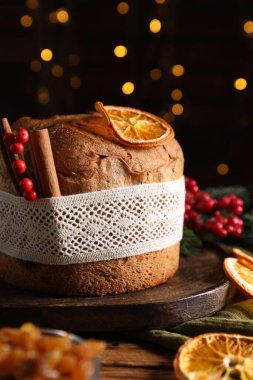 Noel yemeği. Lezzetli Panettone pastası, malzemeler ve ahşap masanın üzerindeki dekoratif dekor arka planda bulanık ışıklar, yakın plan. Bokeh etkisi