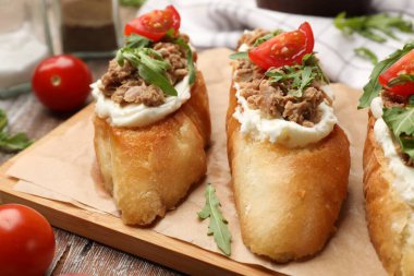 Lezzetli bruschettalar, ton balığı, krem peynir ve domatesler ahşap masada, yakın plan.