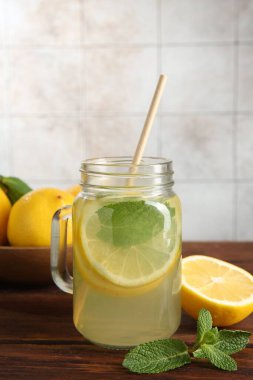 Mason kavanozunda taze limonata, ahşap masada limon ve nane, yakın plan.