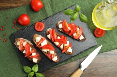 Domatesli lezzetli bruschettalar, mozzarella peyniri ve fesleğen ahşap masada servis edilir.