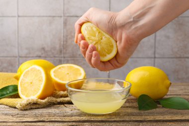 Bir kadın ahşap masada limondan klozete meyve suyu sıkıyor.