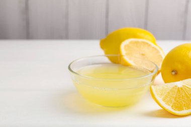 Bardakta limon suyu ve beyaz ahşap masada taze limon, yakın plan. Metin için boşluk