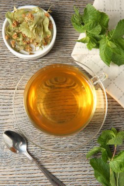 Cam fincanda lezzetli çay, ıhlamur, nane ve çay kaşığı ahşap masada, düz yatıyordu.