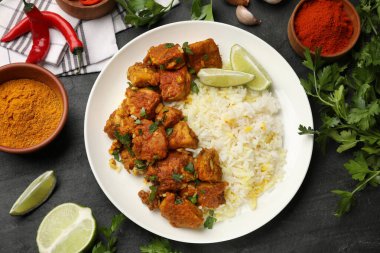Lezzetli tavuk tikka masala ile pirinç, maydanoz, kireç ve baharatlar koyu dokulu masa, düz uzanma