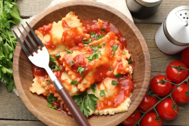 Ahşap masada servis edilen domates soslu ve maydanozlu lezzetli ravioli.