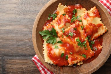 Domates soslu lezzetli ravioli ve ahşap masada maydanoz.