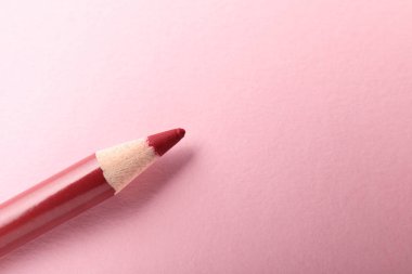 Pembe arka planda kırmızı göz kalemi, üst manzara. Metin için boşluk