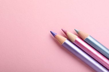 Pembe arka planda farklı göz kalemleri, düz yatış. Metin için boşluk