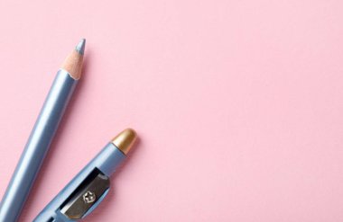 Açık mavi göz kalemi ve pembe arka planda keskinleştirici, düz yatıyordu. Metin için boşluk