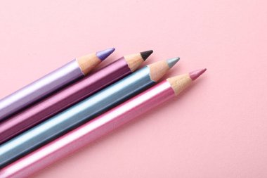 Pembe arka planda parlak göz kalemleri, düz yatış. Metin için boşluk