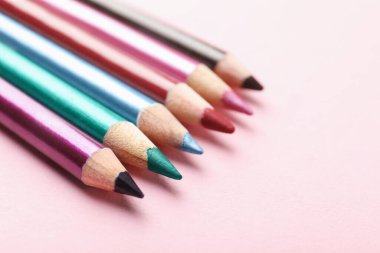 Pembe arka planda parlak göz kalemleri, yakın plan. Metin için boşluk