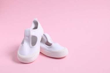 Pembe arka planda bir çift şık çocuk ayakkabısı, yakın plan. Metin için boşluk
