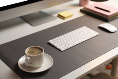 Ofisteki beyaz masada bilgisayar, kahve ve gri hasırlı şık bir iş yeri, yakın plan.