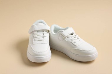 Bej arka planda bir çift şık çocuk ayakkabısı, yakın plan.