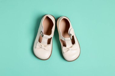 Açık mavi arka planda bir çift şık çocuk ayakkabısı.