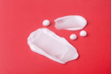 Kırmızı arkaplanda nemlendirici krem örnekleri, yakın plan