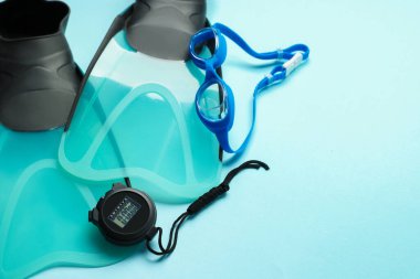 Flippers, dijital kronometre ve açık mavi arka planda gözlükler, düz konum. Metin için boşluk