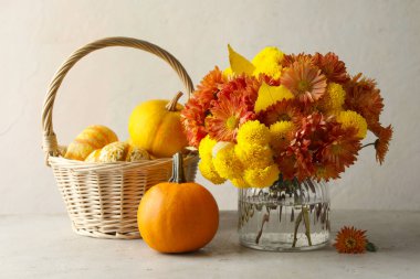 Sonbahar atmosferi. Güzel çiçekli vazo ve açık gri masadaki kabaklar.