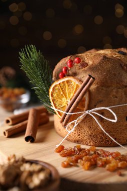 Noel yemeği. Lezzetli Panettone pastası, malzemeler ve arka planda arka planda bulanık ışıklı şenlikli dekor, yakın plan. Bokeh etkisi