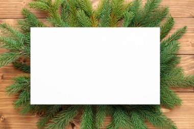 Noel ağacı dalları ve tahta masanın üzerinde boş bir kart, düz bir şekilde yatıyordu. Metin için boşluk