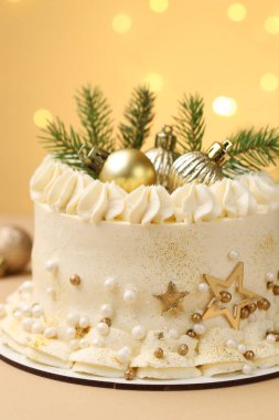 Bej arka planda Noel dekoru olan enfes bir pasta bulanık ışıklara karşı, yakın plan. Bokeh etkisi