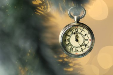 Cep saati ve köknar ağacı dalları altın arka planda bulanık ışıklarla, yakın plan. Yeni yıl tebrik kartı.