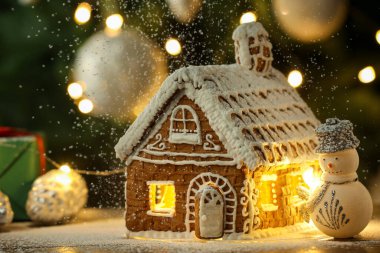 Kremalı ve Noel dekorlu güzel zencefilli ev ahşap masanın arkasında bulanık ışıklarla, yakın plan