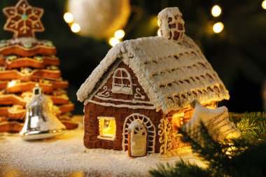 Kremalı ve Noel dekorlu güzel zencefilli ev ahşap masanın arkasında bulanık ışıklarla, yakın plan