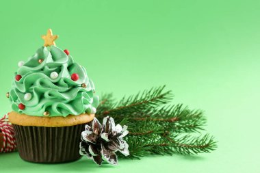Noel ağacı şekilli kek ve yeşil arka planda şenlikli dekor, yakın plan.