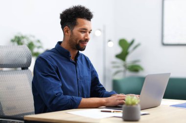 ofiste masada dizüstü bilgisayarda çalışan adam